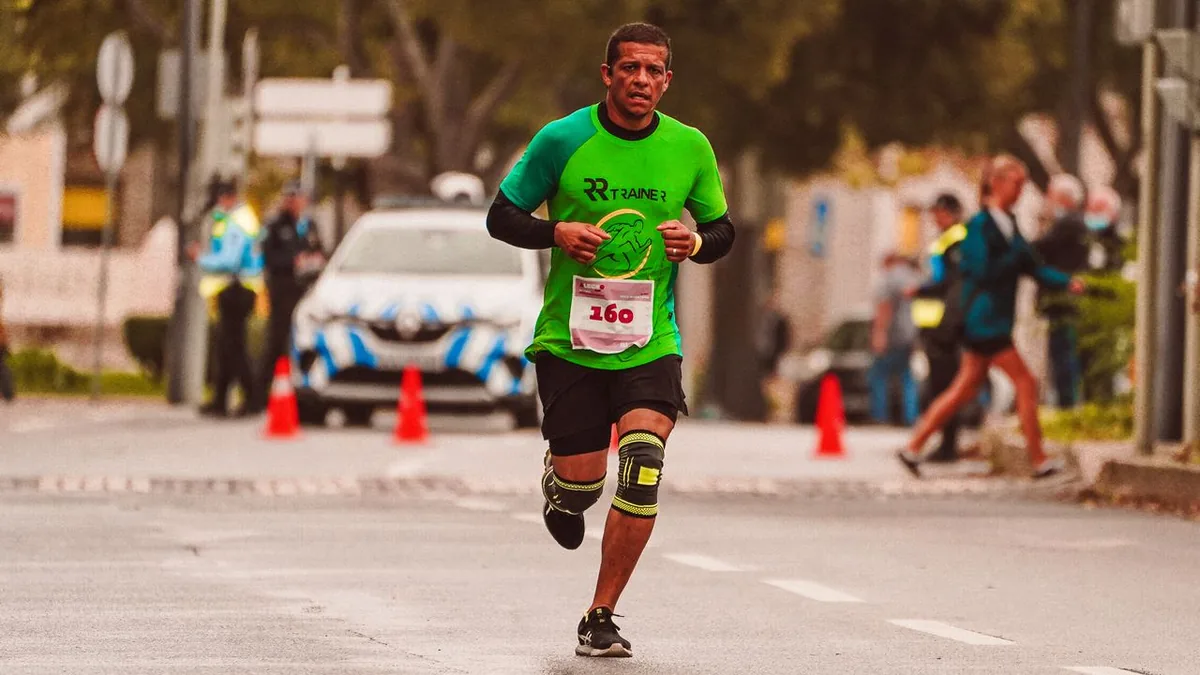 Coureur en pleine course sur route, le visage tendu, genouillères aux deux jambes