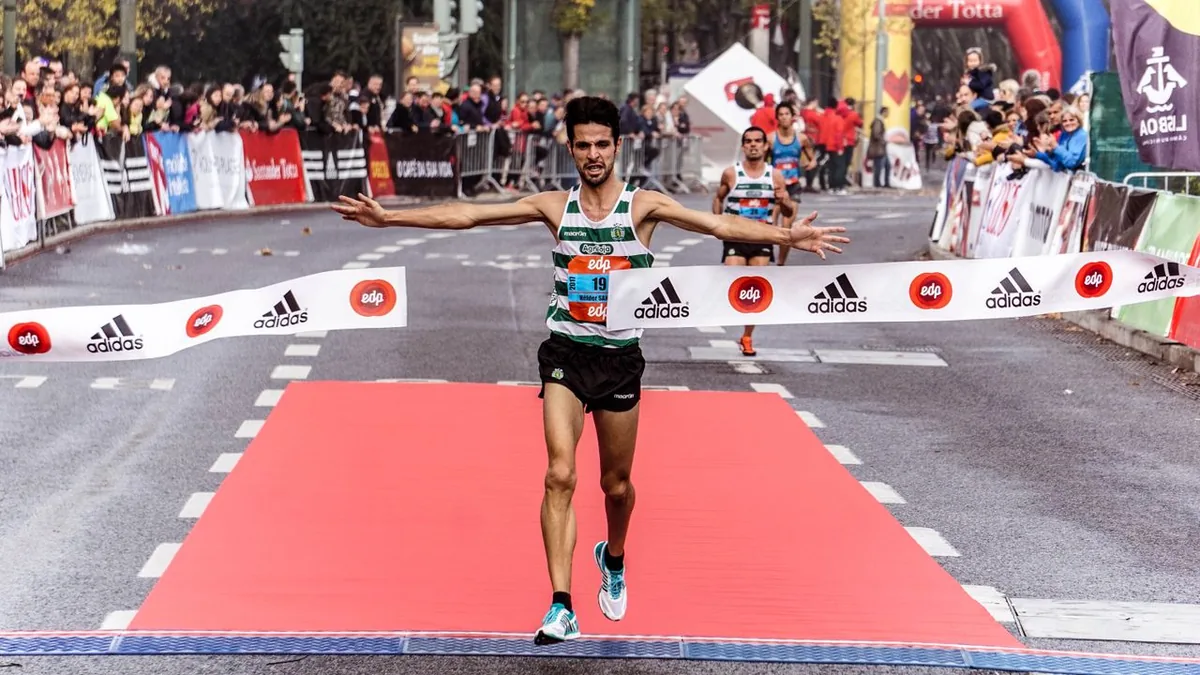 Coureur qui franchit la ligne d'arrivée d'une course sur route, bras écartés