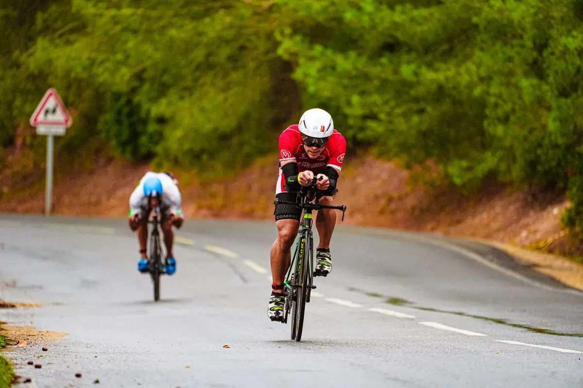 Cycliste en descente sous la pluie sur route mouillée lors d'un triathlon