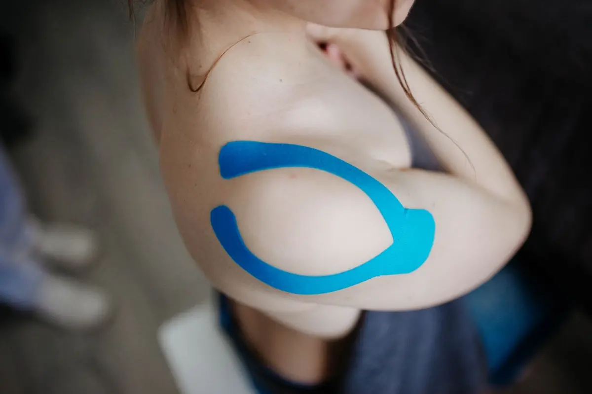 Sportive avec taping bleu sur l'épaule, signe d'une blessure en cours de guérison
